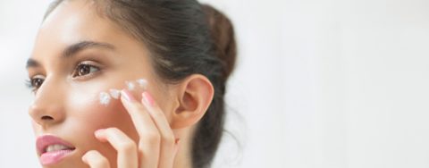 Woman applying moisturizer to cheek