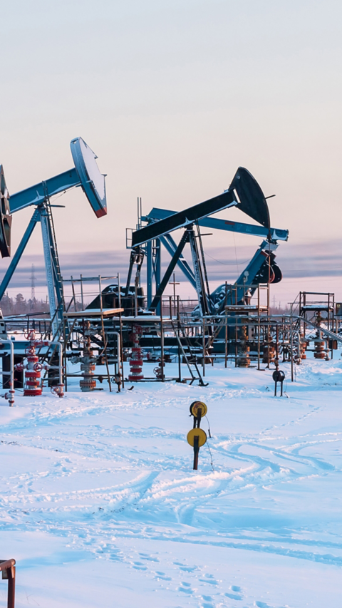 Oil Field. Winter industrial landscape with an oil pump and torch in the background.