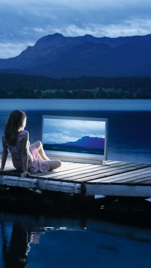 Woman watching widescreen monitor displaying scene surrounding itself