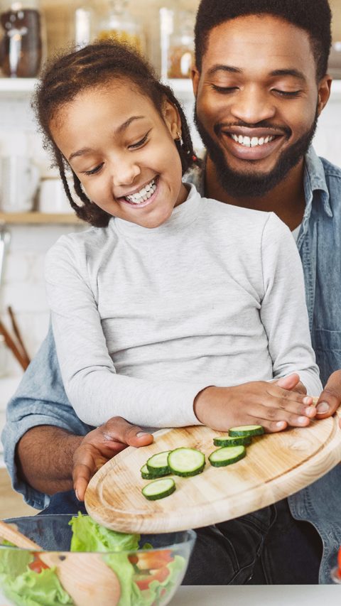 Cute little afro girl and his father making salad together. Happy childhood concept, copy space; Shutterstock ID 1397569916; purchase_order: -; job: -; client: -; other: -