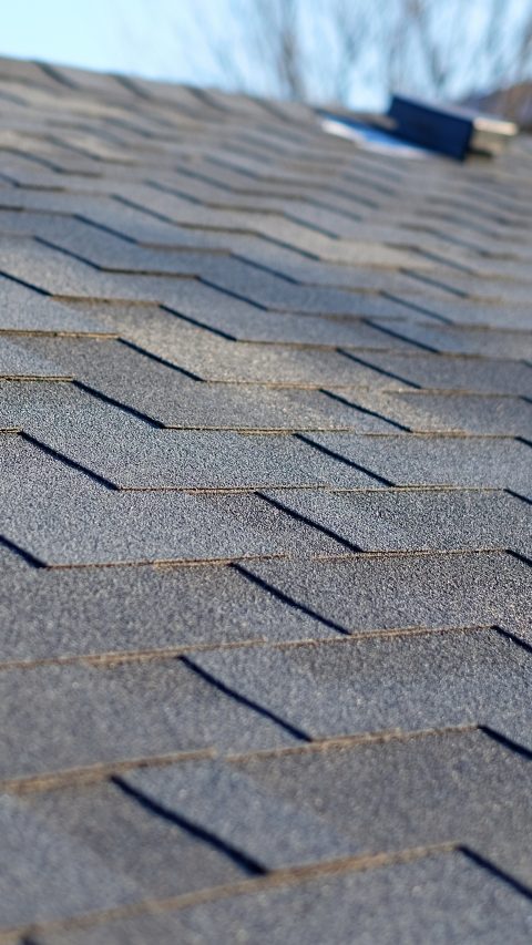Bitumen tile roof. Roof Shingles - Roofing. Close up view on Asphalt Roofing Shingles .