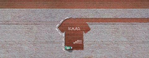 Das Bild ist eine Luftansicht eines Baumwollfeldes, in dem eine Erntemaschine arbeitet. Der Boden, wo die Baumwolle geerntet wurde, hat die Form eines T-Shirts. Auf dem Bild befinden sich weiße handschriftliche Skizzen mit chemischer Summenformel und drei Pfeilen.