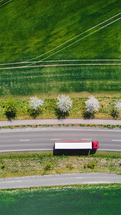 Drone shot direct above a truck moves along a single road.