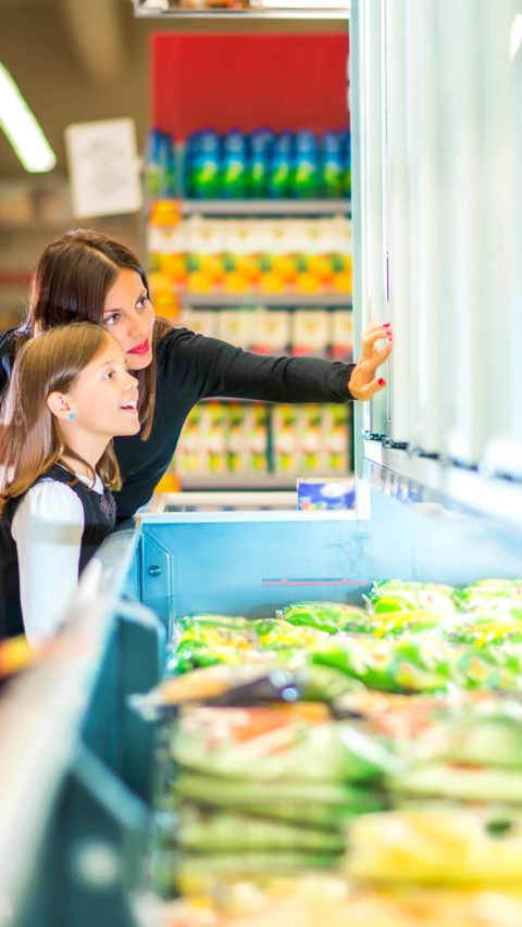 Mother and daughter in supermarket near frozen food
