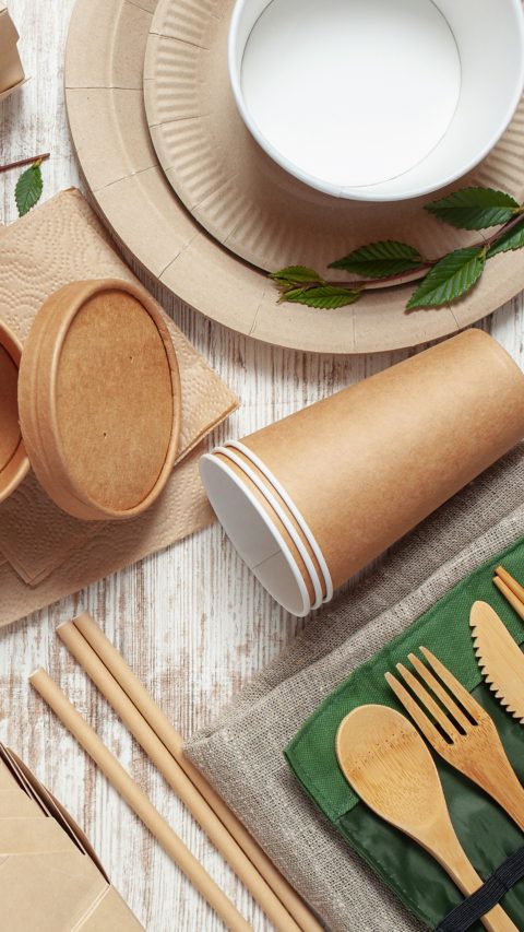 Eco craft paper tableware. Paper cups, dishes, bag, fast food containers and wooden cutlery on pink background. Recycling or zero waste concept. Top view. Copy space