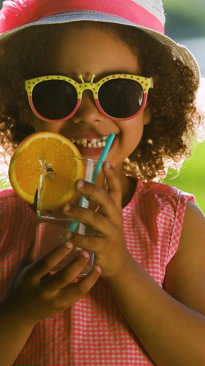 Natural Beverage Ingredients - Photo of two girls with sun hats and sunglasses drinking with from fruit juice with straws