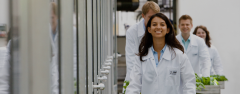 Eine lächelnde junge Frau in Laborkleidung. 